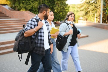 Fototapeta premium Portrait of three multi-ethnic university students embracing together standing in the campus