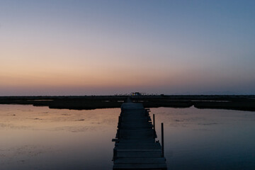 Obraz premium a narrow wooden bridge over a body of water at sunset near the island of Lefkada in Greece