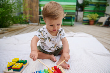 Adorable baby playing with educational wooden toys outdoors