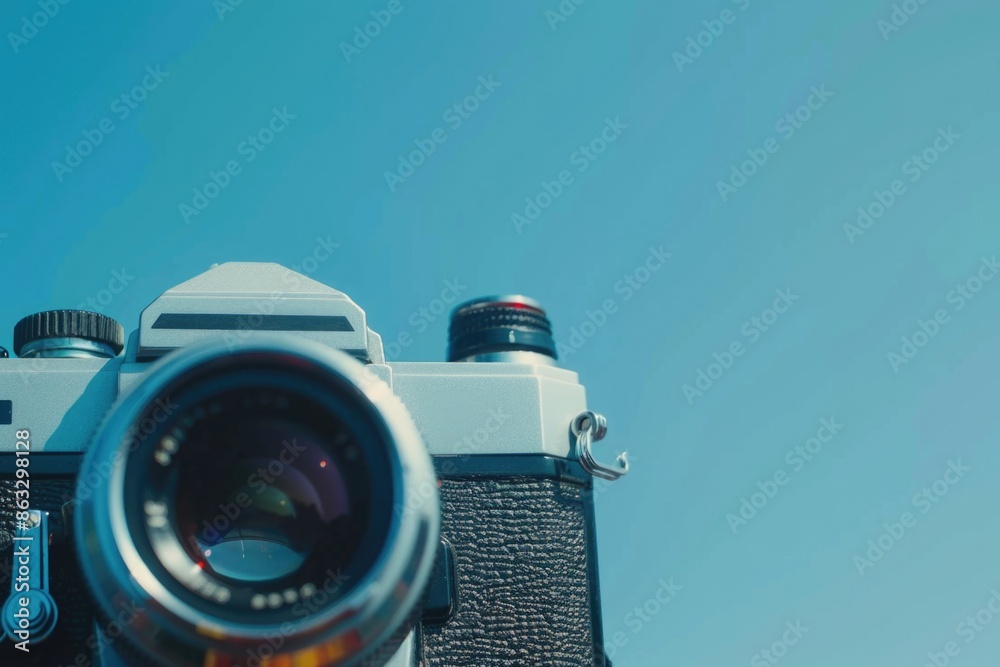 Poster a detailed view of a camera with a blue sky in the background, suitable for use as a symbol or icon