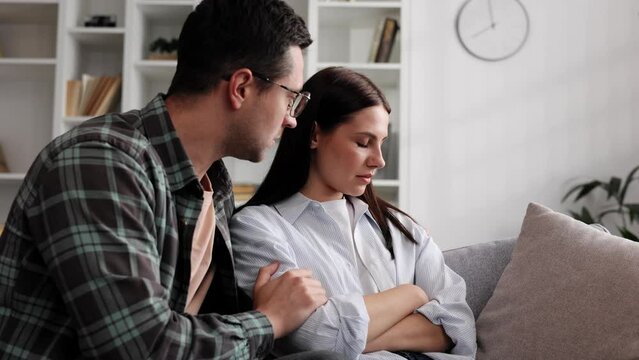 A sympathetic young man provides psychological support to a thoughtful upset loved woman in a difficult life situation, showing loving care, overcoming grief together, or apologizing indoors.