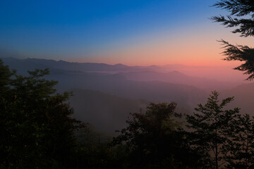 Landscape horizon line in the mountains, orange sunset and blue mountains.