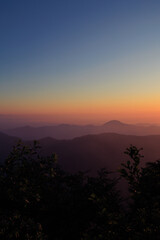 Landscape horizon line in the mountains, orange sunset and blue mountains.