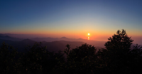 Landscape horizon line in the mountains, orange sunset and blue mountains.