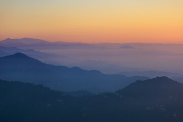 Landscape horizon line in the mountains, orange sunset and blue mountains.