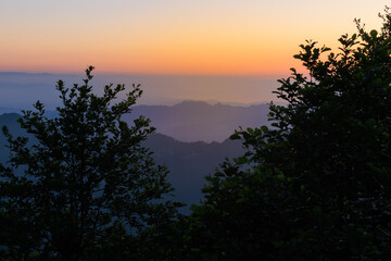 Landscape horizon line in the mountains, orange sunset and blue mountains.