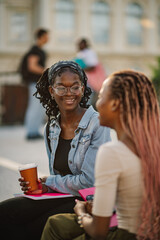 Close up of happy interracial students sitting on stairs and chatting.