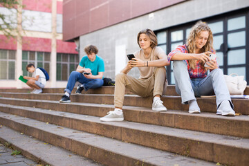 Boy and girl playing on smartphones during recess between college classes