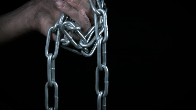 Chained hands with no freedom. A view of chained dirty hands fighting from freedom against black background.