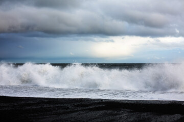 Black beach. Rocks in the water. Black stones in the ocean.