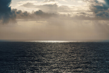 Fototapeta premium The sun is casting its rays through the clouds onto the ocean