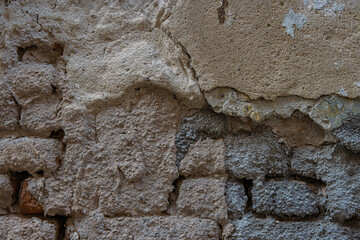 Old damaged broken shabby red brick wall of an old building. Brick texture with scratches and cracks. Grunge background with cracked grey blueish stucco.  Close up. Copy space