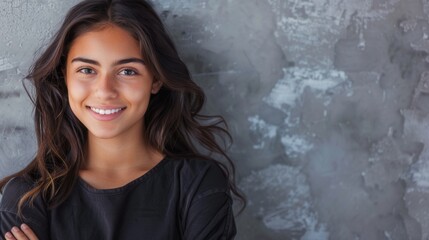 Fototapeta premium A young Hispanic woman with long brown hair smiles confidently while standing in front of a grey wall, arms crossed. Generative AI