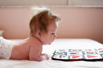 2-month-old newborn baby girl looking at high-contrast pictures during tummy time. Baby early learning. Newborn development