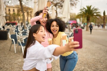 Young women enjoying ice cream and taking selfie outdoors