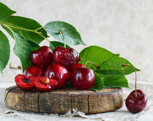 Ripe cherries, cherries on a wooden board with leaves, light background, close-up. A healthy summer dessert.