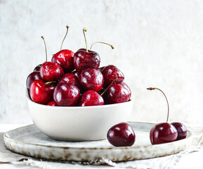 Ripe cherries in a ceramic vase on a light background close-up. A healthy summer dessert.