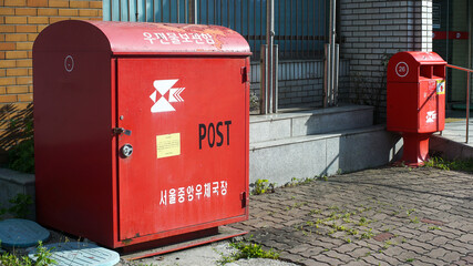 Two red mailboxes in front of a post office in Seoul, Korea