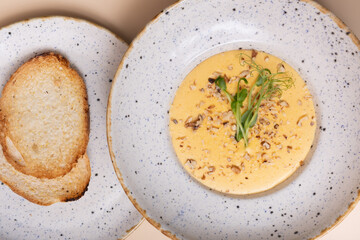 Close up plate of cheese cream soup with nuts and micro greens