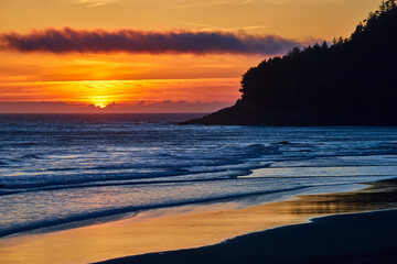 Obraz premium Sunset Over Ocean With Promontory Silhouette From Shore