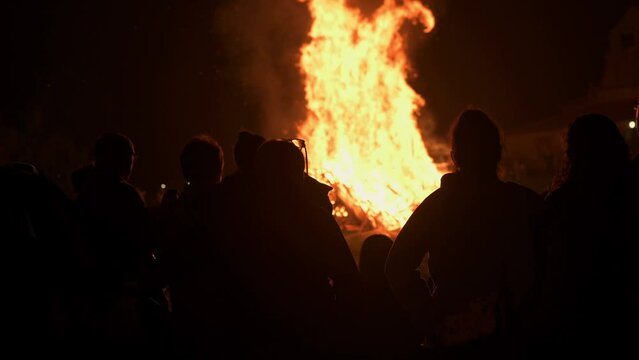silhouettes of unrecognizable people observing a large bonfire during the night of san juan in the principality of asturias, Spain. Ancient pagan festival of Litha. 