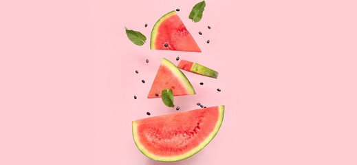 Flying slices of fresh watermelon and mint leaves on pink background
