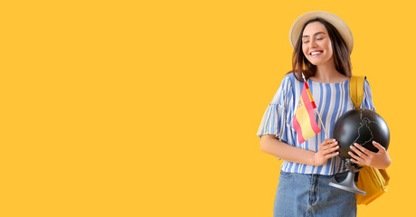 Young woman with flag of Spain, globe and backpack on yellow background