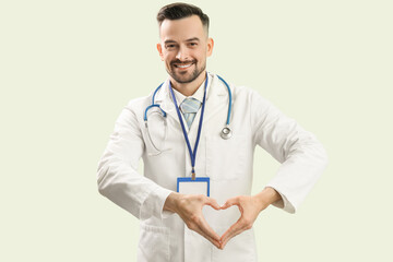 Male doctor making heart with his hands on green background