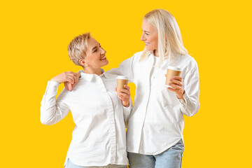 Beautiful mature women with coffee on yellow background