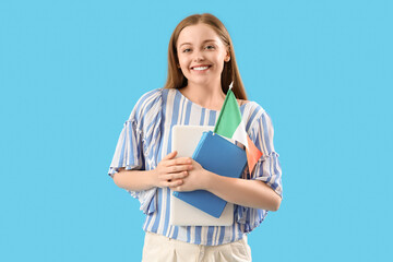 Young female student with flag of Italy and books on light blue background