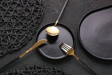 Plate with golden cutlery on black background