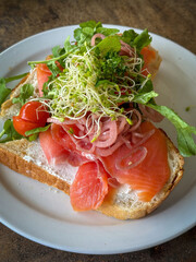 Breakfast toast with smoked salmon and greens served on a white plate