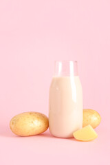 Bottle of tasty potato milk on pink background