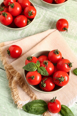 Bowls with fresh cherry tomatoes and basil on green wooden table