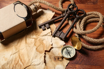 Bottle of rum with travel equipment and keys on brown wooden background © Pixel-Shot