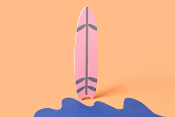 Creative composition with paper waves and mini surfboard on pale orange background