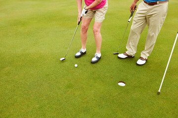 Obraz premium Outdoor, golf club and legs on green for tee off in team as members in course for health, wellness or fitness. People, putter and hole for sports, exercise or training as athlete in challenge or game