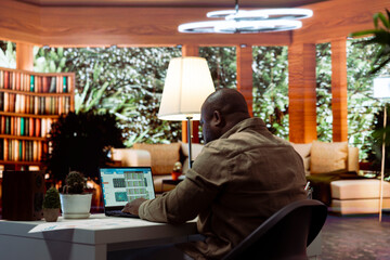 Corporate businessman looking into project details and timetables on laptop at his home, establishing budget and operations to achieve startup goals in a competitive environment.