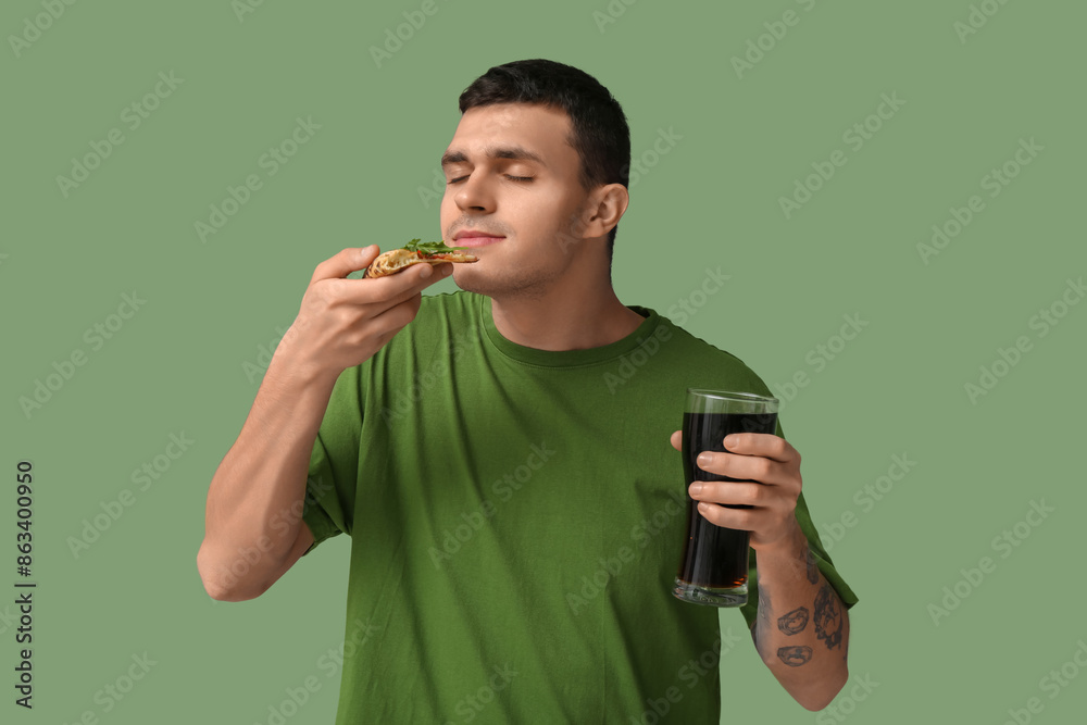 Wall mural young man with piece of tasty pizza and glass of cola on green background