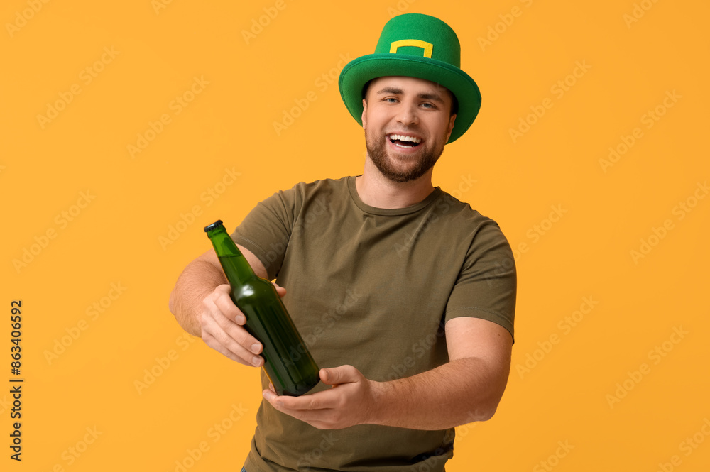 Wall mural happy young man in leprechaun's hat with bottle of beer on yellow background. st. patrick's day cele