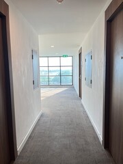Interior of a hotel corridor with white walls and gray carpet.
