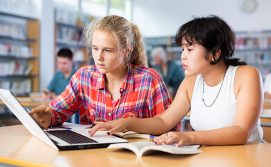 Fototapeta premium Teaching teenagers in the school library using a laptop
