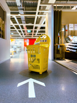 Munich, Germany - Apr 12, 2024: An IKEA shopping cart is left on the vinyl floor with an illuminated arrow inside the Swedish furniture store, emphasizing the store's navigational design 