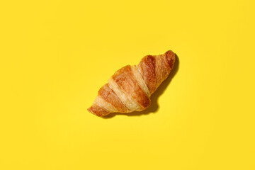 Tasty croissant on yellow background