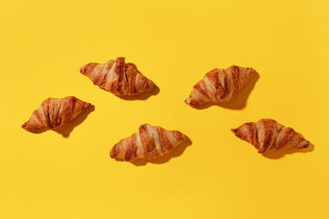 Many tasty croissants on yellow background