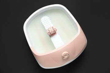 Massage foot bath on black background
