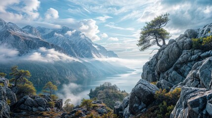 Obraz premium Scenic mountain landscape with a tree on a rocky outcrop and mist over a lake