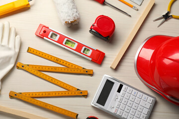 Flat lay composition with building level and other construction tools on white wooden table
