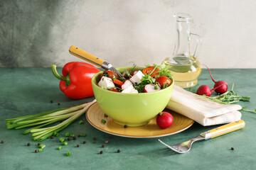 Bowl of fresh vegetable salad with radish and feta cheese on green table
