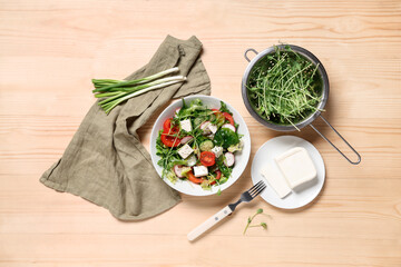 Bowl of fresh vegetable salad with radish and feta cheese on wooden background
